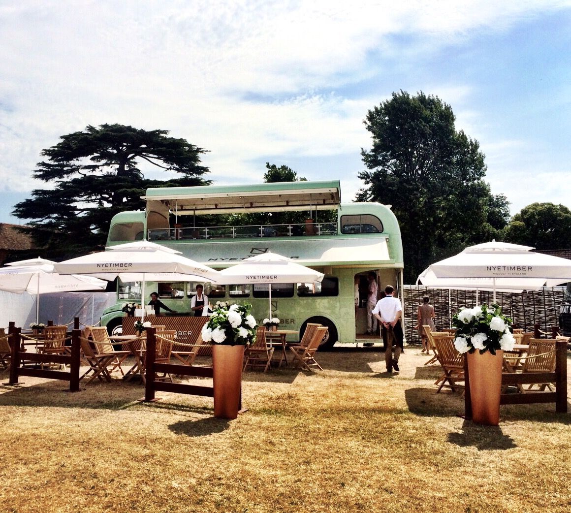 a green vintage open top bus, set out for dining with chairs, tables and parasols, decorated with white flowers