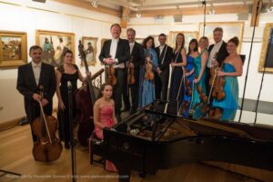 group of musicians, holding instruments, stood behind a piano