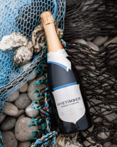 wine bottle laid on fishing net and pebbles