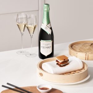 a table setting with small dessert and a bottle of Nyetimber Cuvee Chérie next to two full wine glasses