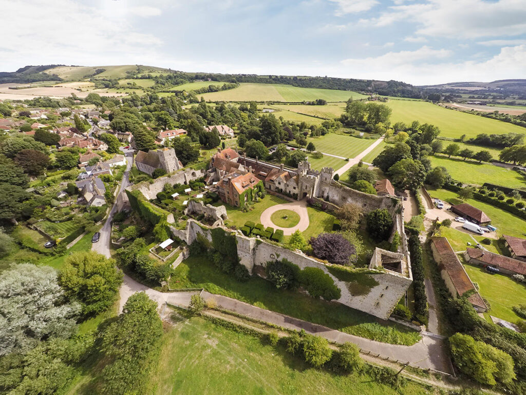 the overhead view of historic castle grounds with lawns and outbuildings situated in a village